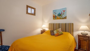 Een kamer met een groot bed, twee nachtkastjes met lampen, een raam en een schilderij aan de muur.