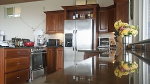 A modern kitchen with stainless steel appliances, wooden cabinets, and a polished granite countertop.