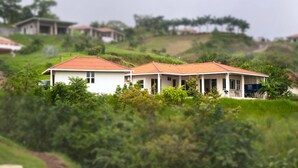 A residential area with houses on a hillside, surrounded by greenery.