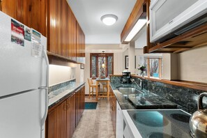 A compact kitchen with wooden cabinets, a built-in microwave, and a granite countertop.