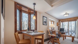 A cozy living room with a wooden dining table, chairs, a TV, and a fireplace. - RMR: Sagebrush 1311 Condo in The Aspens/Wilson,WY (Wilson)