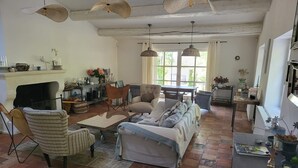 Ein geräumiges Wohnzimmer mit Kamin, einer Couch, einem Esstisch und einer Küchenzeile.