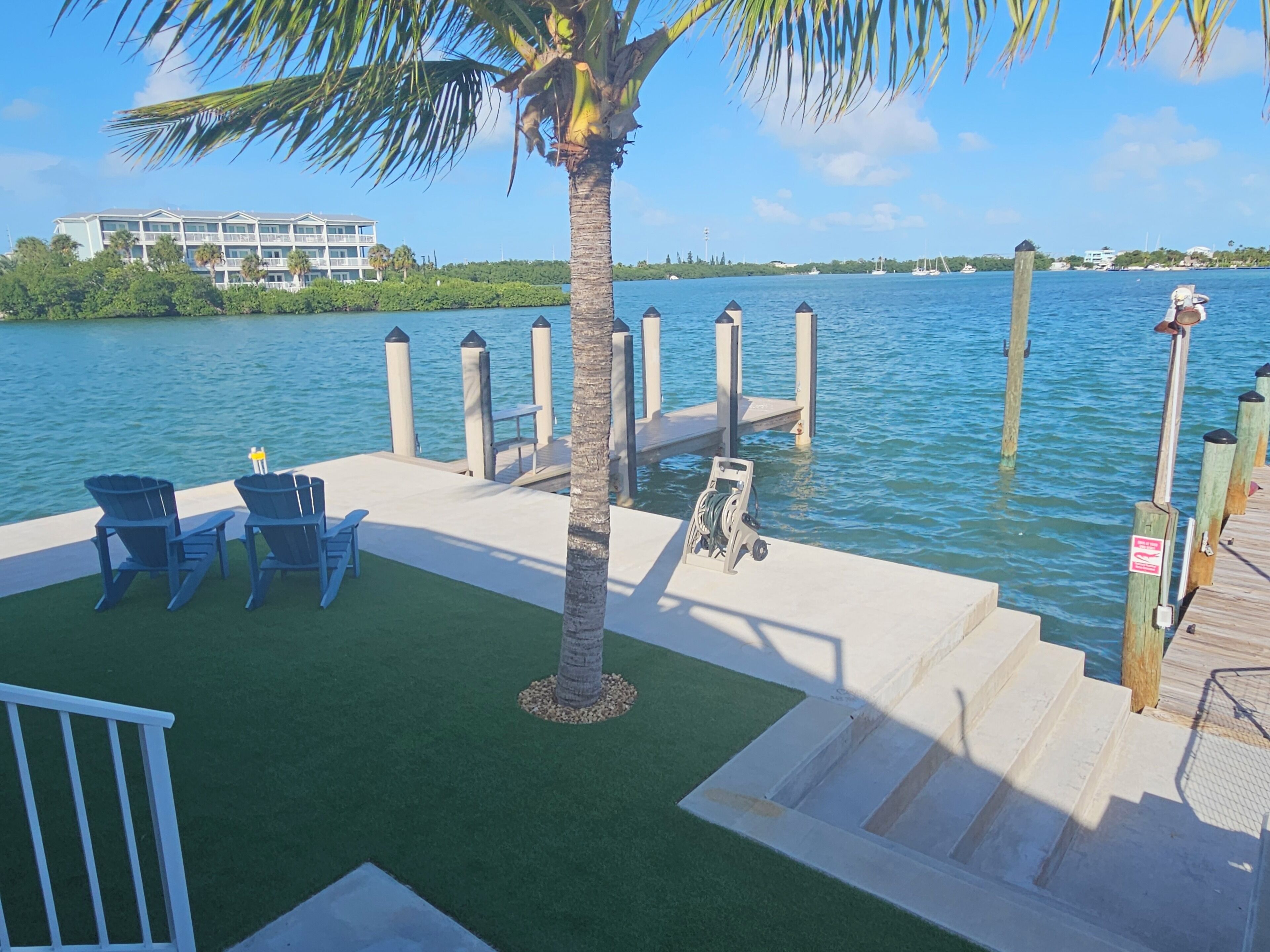 A dock with chairs and a palm tree, leading to a pier with steps.