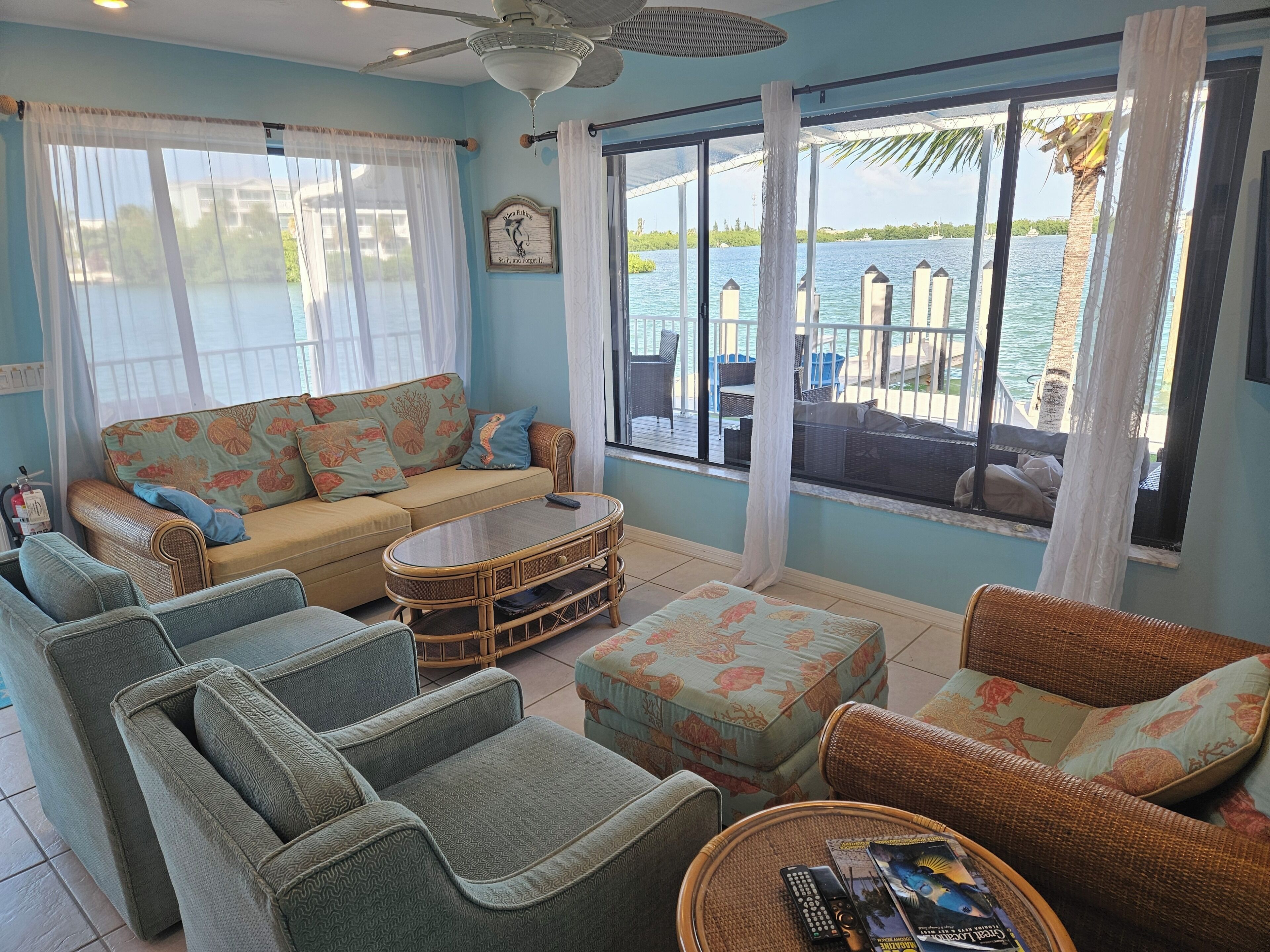 A room with a sofa, chairs, a coffee table, and a view of the water.