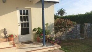 Une maison avec une porte blanche, un petit porche avec des marches et des plantes en pot.