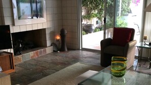 A living room with a fireplace, a television mounted on the wall, a sofa, and a glass coffee table. - Location, location, location!  El Paseo Jewel in the desert  (Palm Desert)