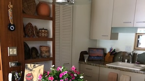 A kitchen with granite countertops, a bar stool, a potted plant, and a hanging light fixture. - Location, location, location!  El Paseo Jewel in the desert  (Palm Desert)