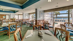 Un restaurant avec des tables et des chaises, de grandes fenêtres donnant sur l’océan et un plafond doté d’un éclairage encastré.