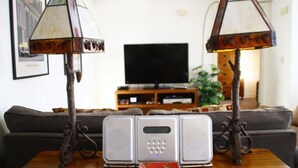 Une table en bois, deux lampes, un téléviseur et un système audio dans un salon.