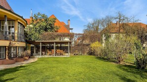 Une pelouse bien entretenue, un patio couvert et un bâtiment surmonté d’un toit en tuiles rouges.