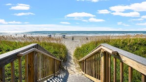 A wooden boardwalk leading to a beach with people walking and sitting. - Beautiful Oceanfront Condo, Jacuzzi Tub, Outdoor Pool | South Shore Villas - 501 (North Myrtle Beach)