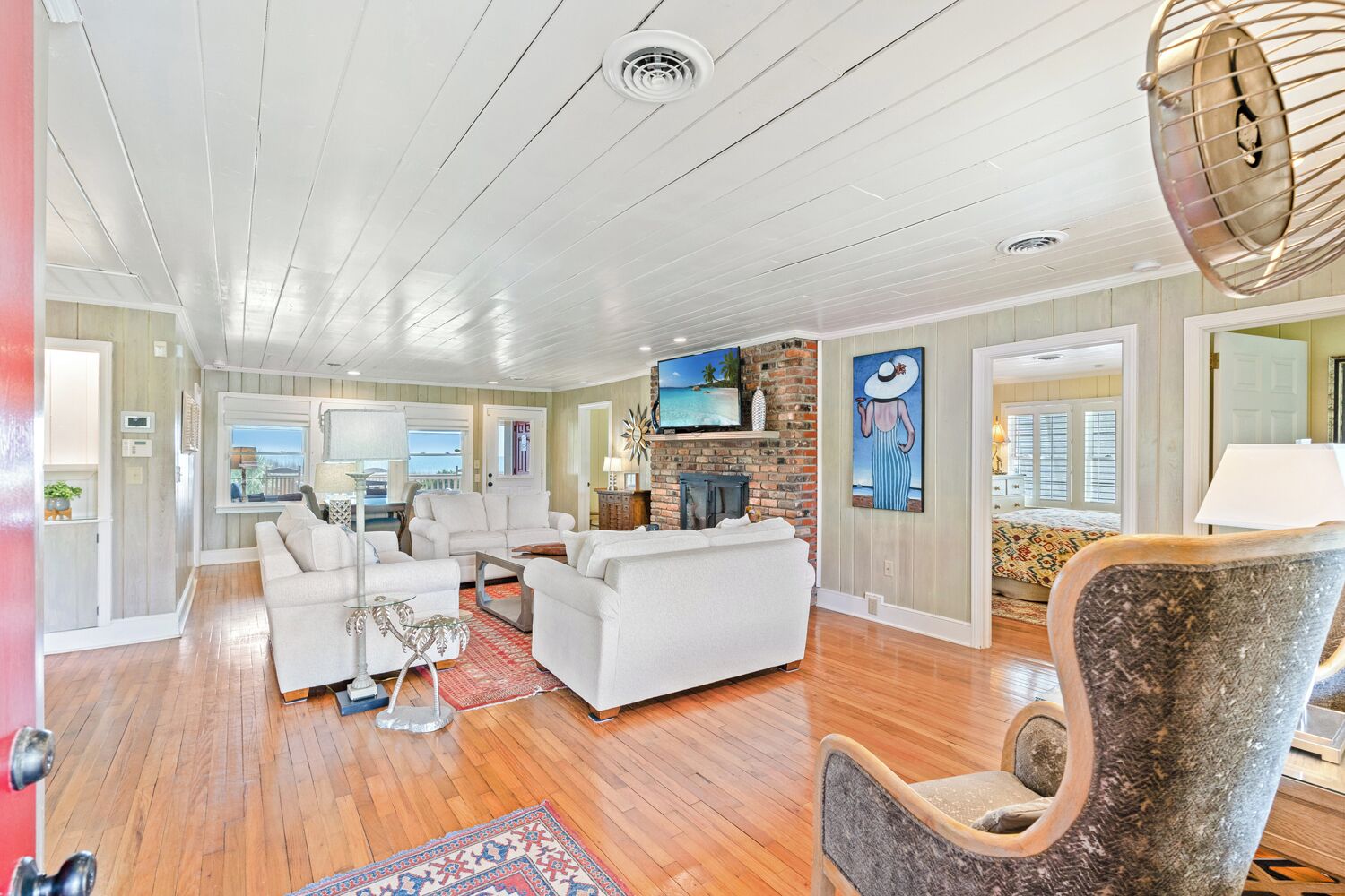 A spacious living room with a fireplace, white furniture, and a large TV.