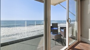 Un balcon avec une porte vitrée donnant sur la plage.