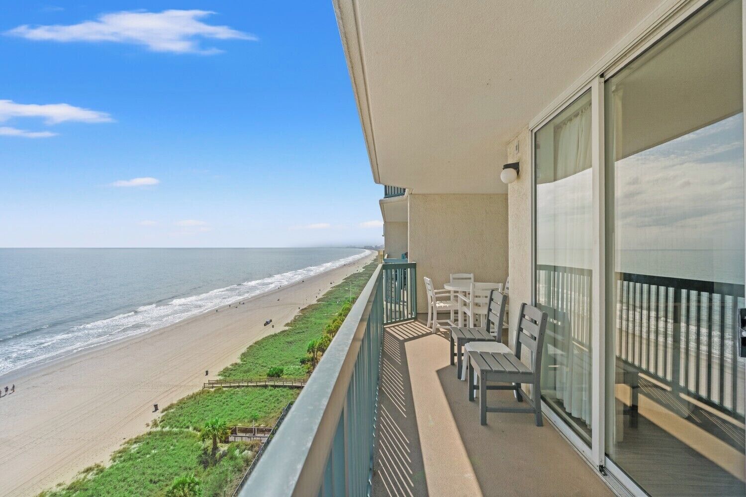 A balcony with a view of the beach and ocean.