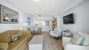 En moderne stue med sofa, sofabord og et fjernsyn ophængt på væggen.