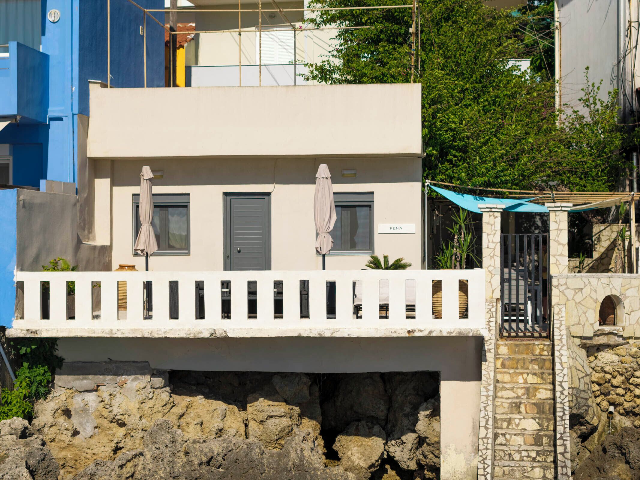 A two-story building with a balcony, a stone wall, and a gate.