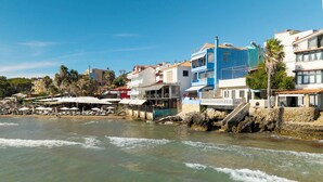 Un poble costaner amb edificis, una platja i embarcacions.
