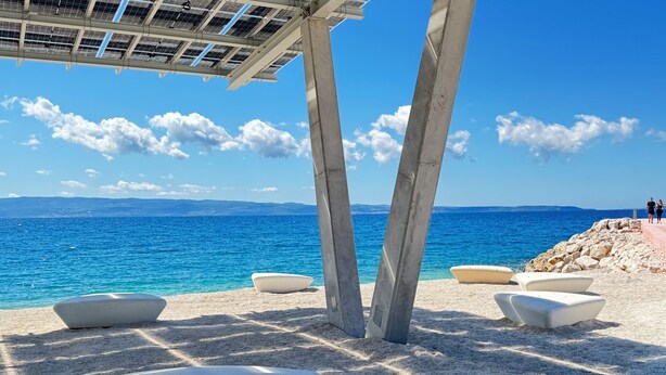A beach with a concrete structure, seating areas, and a view of the sea. - Deluxe beach suite with hot tub, 2 minutes away from the beach (Split)