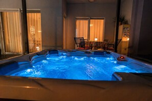 A hot tub with a digital control panel, a table with chairs, and a window with curtains.