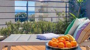 A balcony with a lounge chair, a bowl of oranges, and a white towel. - Deluxe beach suite with hot tub, 2 minutes away from the beach (Split)