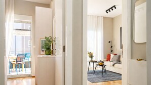 A modern apartment with a wooden floor, a dining area with chairs, a sofa, a small table with a vase, and a plant. - Deluxe beach suite with hot tub, 2 minutes away from the beach (Split)