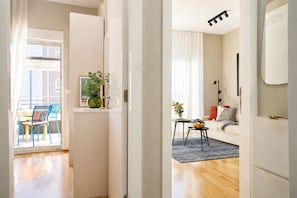 Un appartement moderne avec un plancher en bois, un coin repas avec des chaises, un canapé, une petite table avec un vase et une plante.
