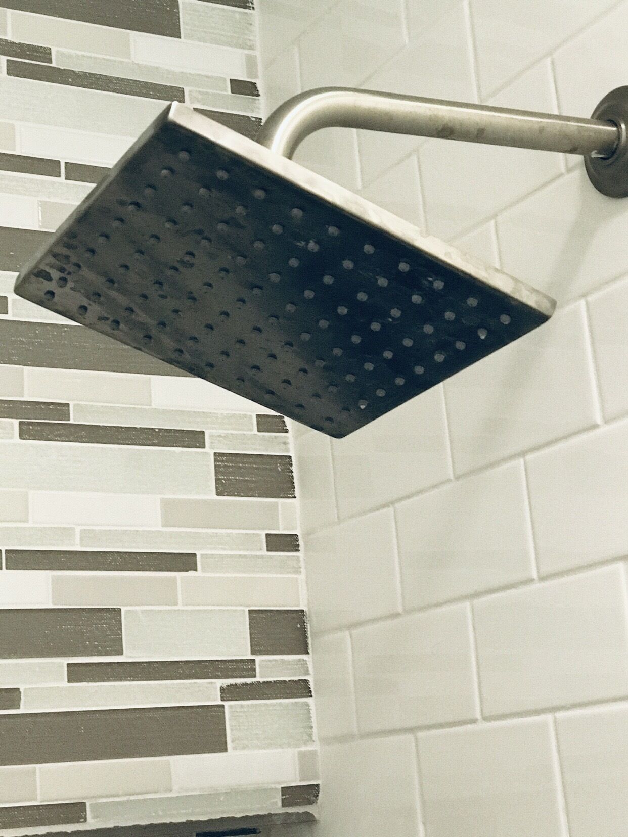 Un cabezal de ducha montado en una pared con salpicadero de azulejos.