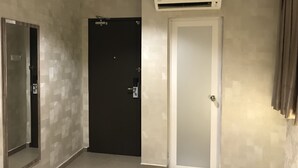 A hallway with a dark door, a white door, and an air conditioning unit mounted on the wall. - Victory Hotel (Johor Bahru)