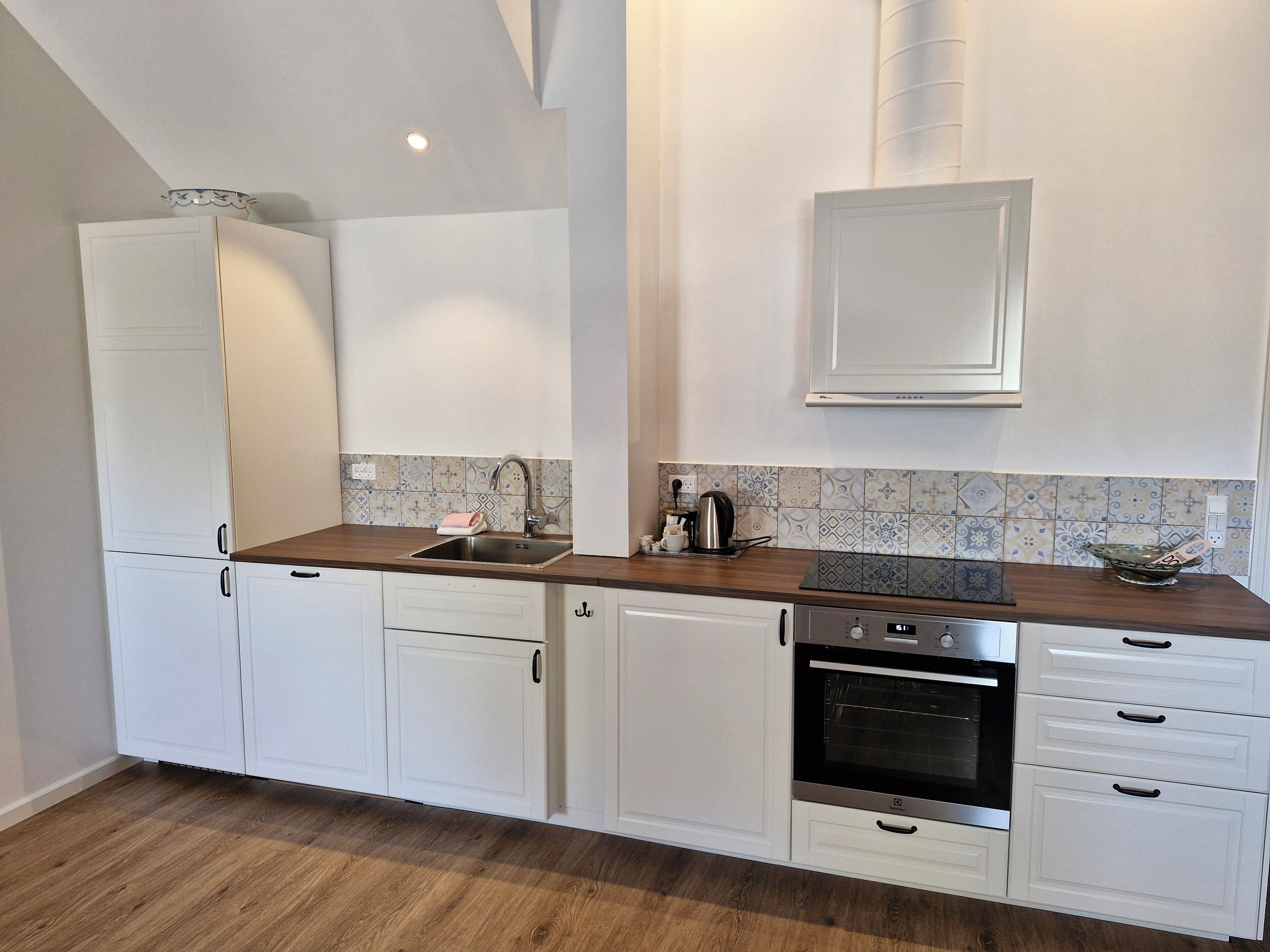A kitchen with white cabinets, a wooden countertop, a stainless steel sink, and an oven.