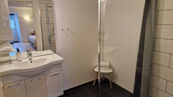 Un baño moderno con lavamanos blanco, espejo y cortina de ducha.