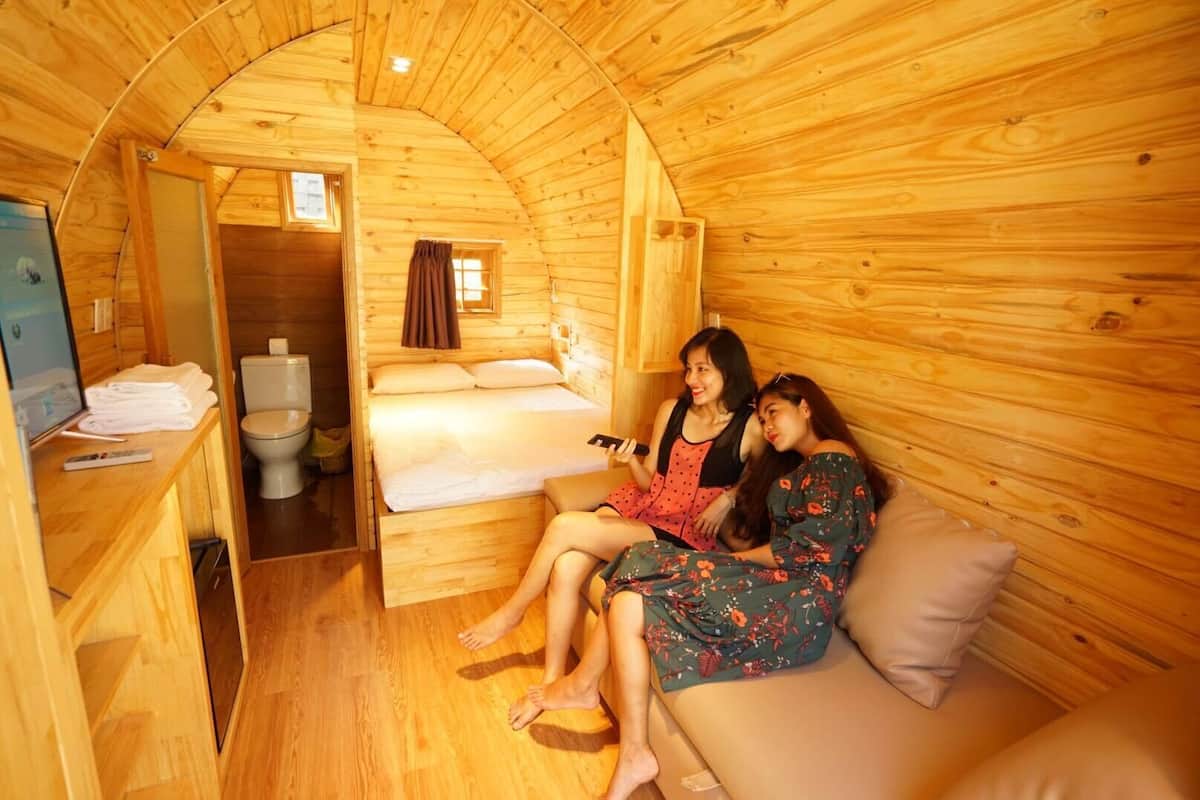 A cozy wooden cabin with a bed, a small bathroom, and a TV on a wooden table.
