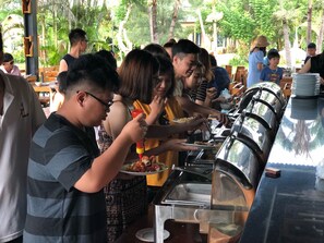 A buffet setup with multiple food stations and people serving themselves. - Longhai Channel Beach Resort (Ho Chi Minh City)