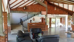 A hotel lobby with a reception desk, a staircase, and leather seating. - Hotel Araliya (Kekirawa)