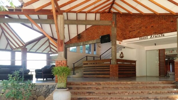 A hotel entrance with a brick facade, wooden staircase, and a large potted plant. - Hotel Araliya (Kekirawa)