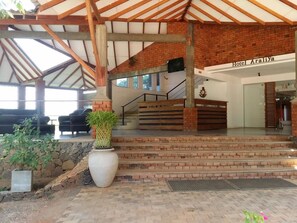 Entrada de hotel con fachada de ladrillo, escalera de madera y una gran planta en maceta.