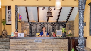 A reception desk with a stone facade, a bell above, and a flag. - Pokhara Boutique Hotel (Pokhara)