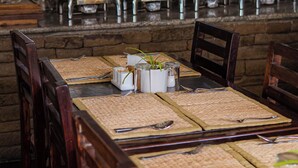 A restaurant with wooden tables and chairs, a buffet setup, and a stone wall. - Pokhara Boutique Hotel (Pokhara)