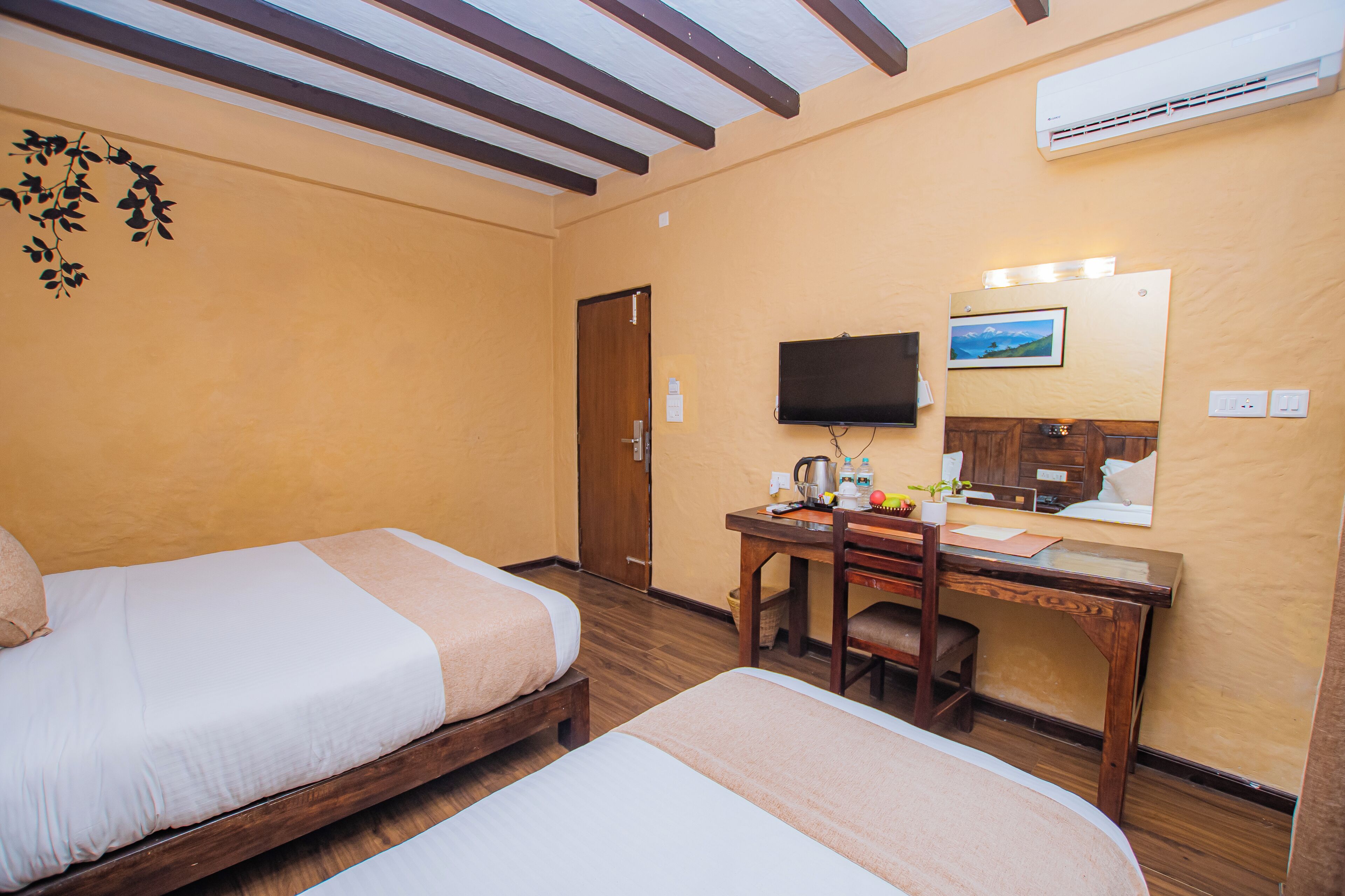 Une chambre d’hôtel avec deux lits, un bureau avec une chaise, une télévision et un appareil de climatisation.