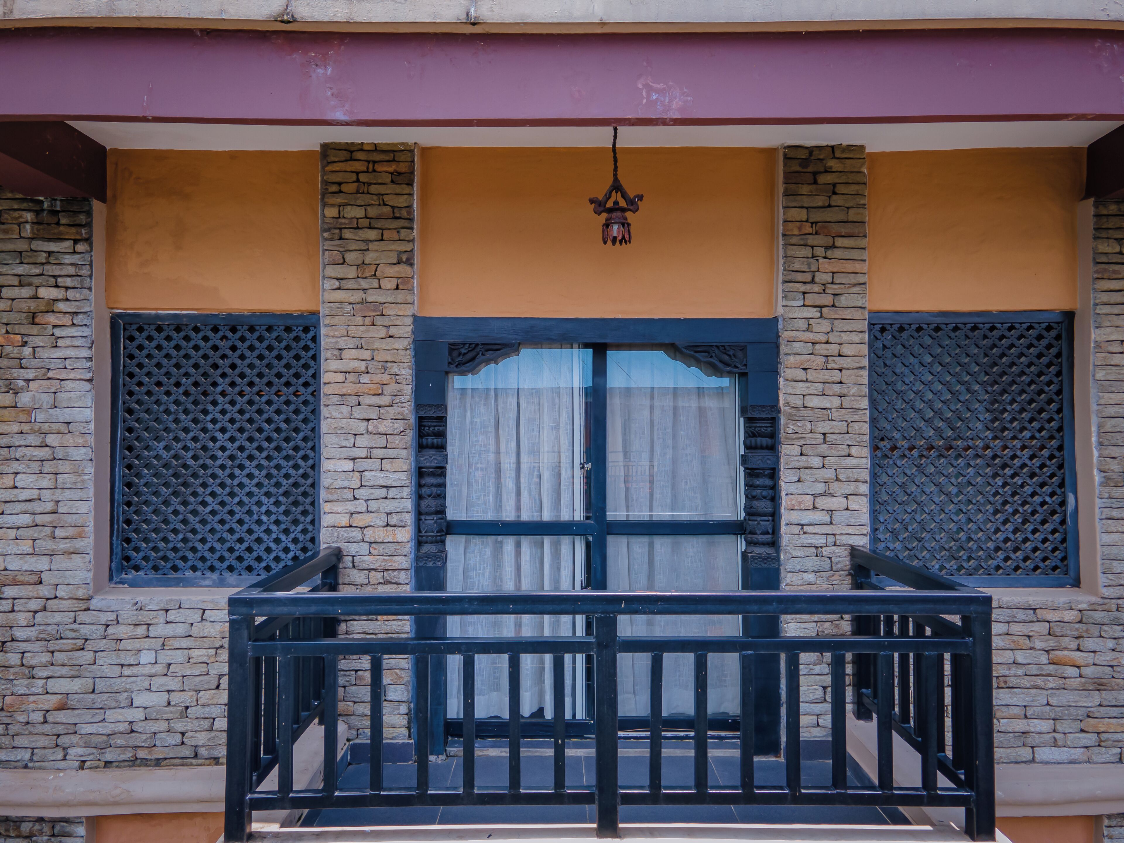 A building facade with a stone and stucco exterior, a central entrance with a black metal gate, and a hanging light fixture above the door.