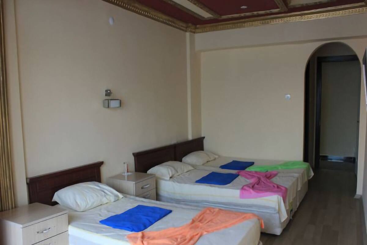 Une chambre d’hôtel avec deux lits, une table de chevet, un petit tiroir et une porte donnant sur une autre pièce.