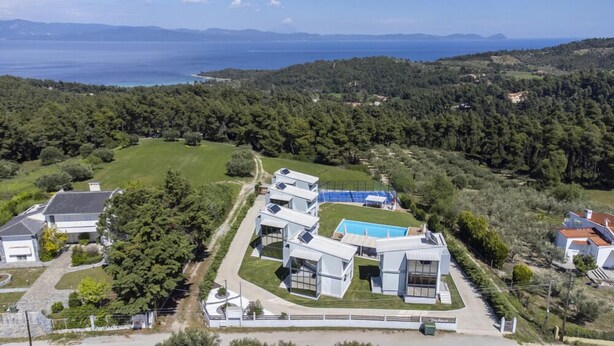 A modern villa with a swimming pool, surrounded by lush greenery and a view of the sea. - Blue Avenue (Kassandra)