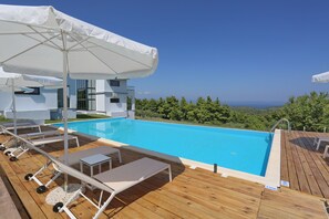 Una piscina al aire libre, sombrillas, sillones reclinables de piscina