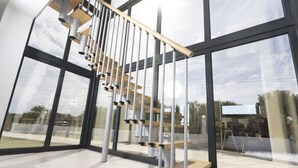 A modern interior with a glass staircase and large windows. - Blue Avenue (Kassandra)