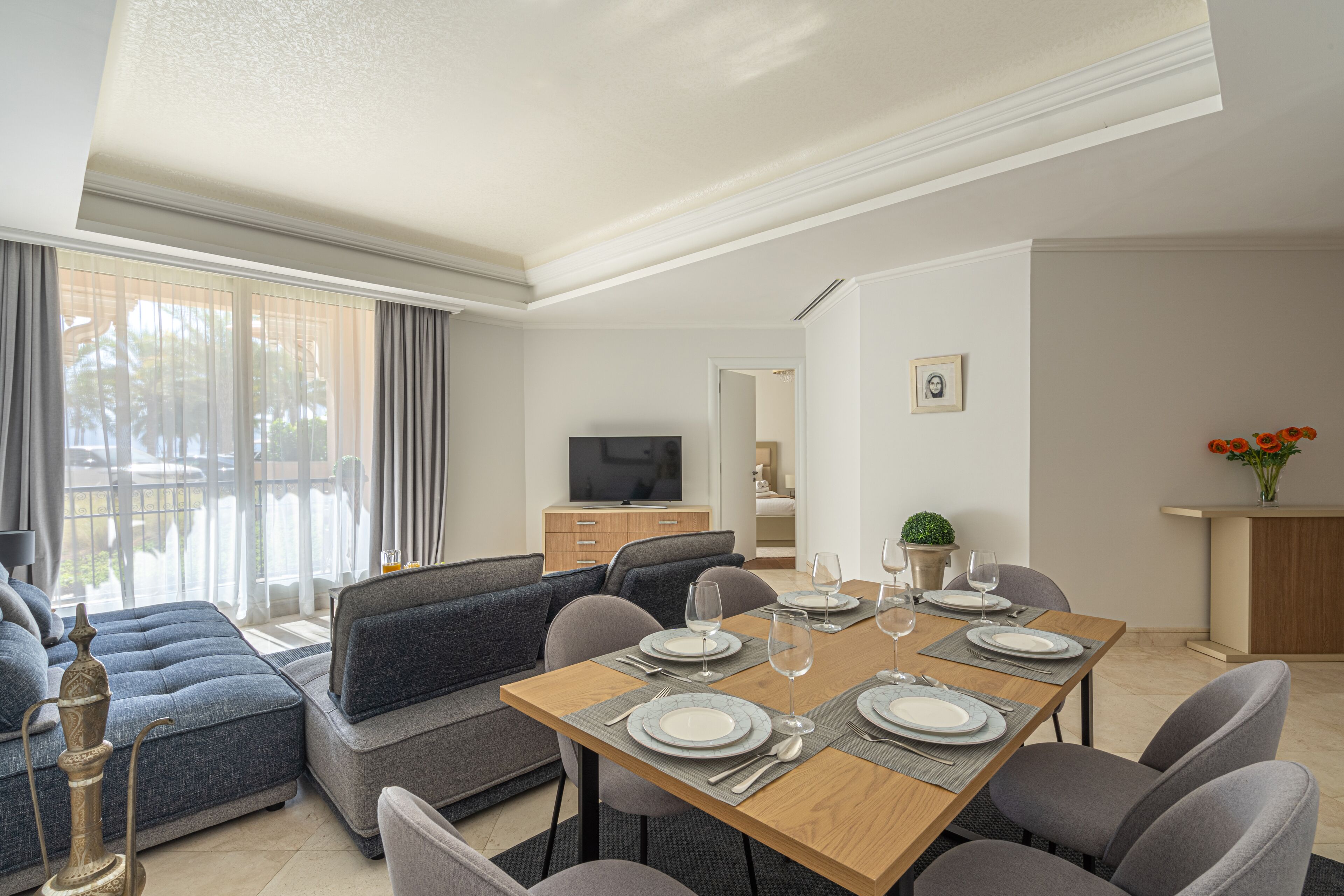 A modern living room with a dining area, a television, and a view of the outdoors.