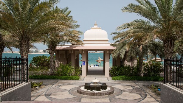 Ein Pavillon mit einem Brunnen, Palmen und Blick aufs Meer.