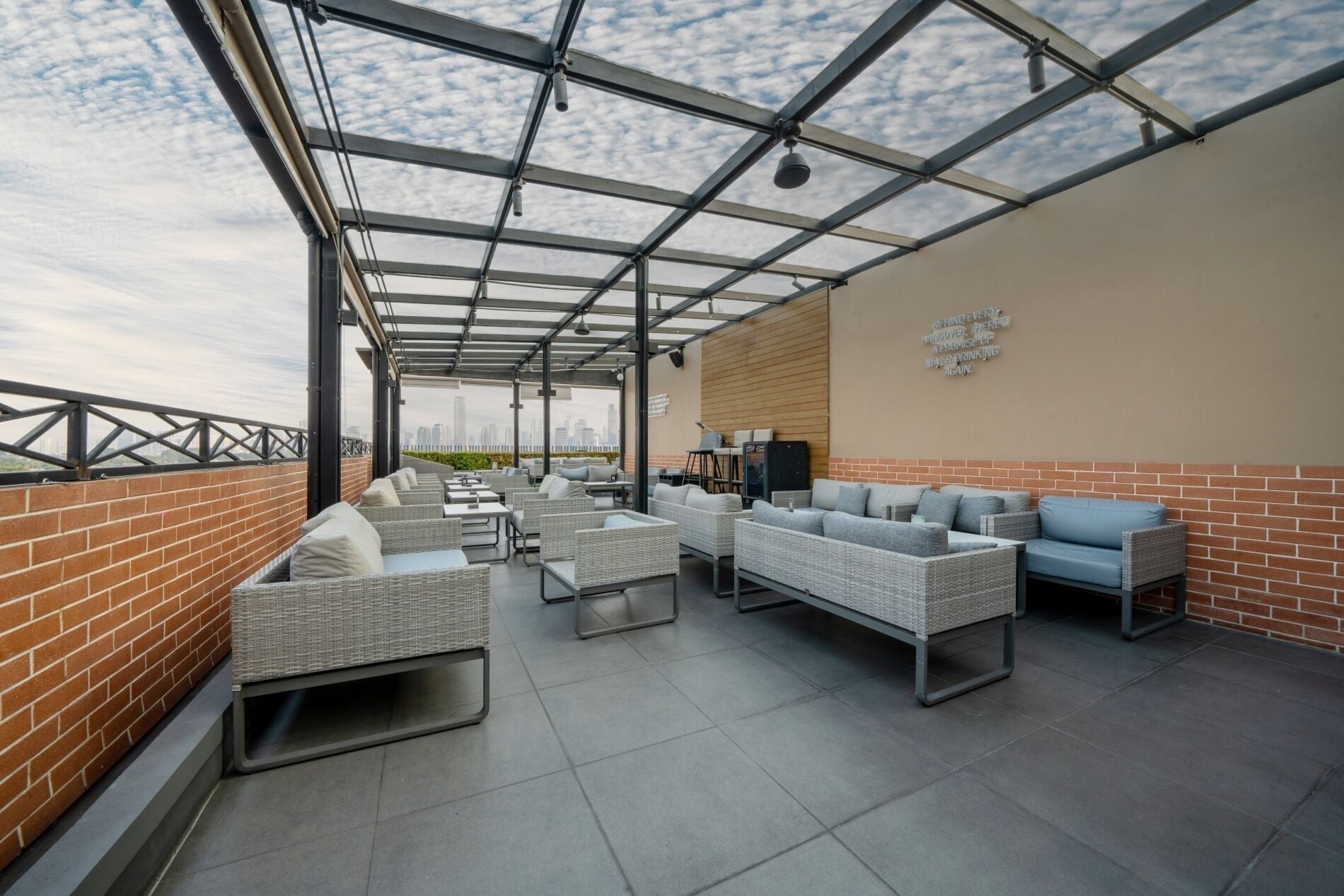 Eine Dachterrasse mit Korbmöbeln, einer Backsteinmauer und Blick auf die Stadt.