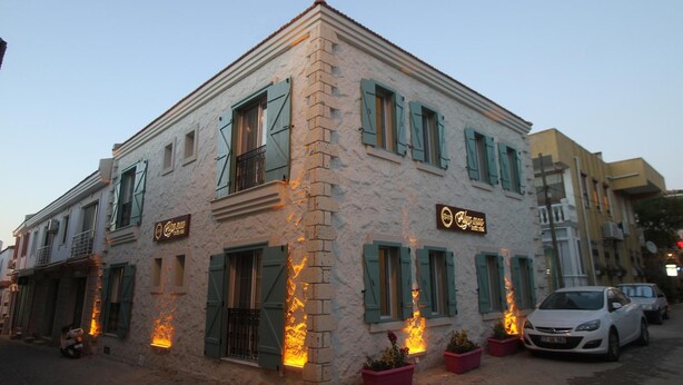 A two-story building with a stone facade, green shutters, and a sign indicating it is a restaurant. - Alya Mou Butik Otel (Cesme)