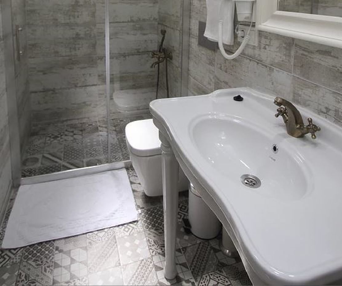 A bathroom with a white sink, a toilet, and a shower area.