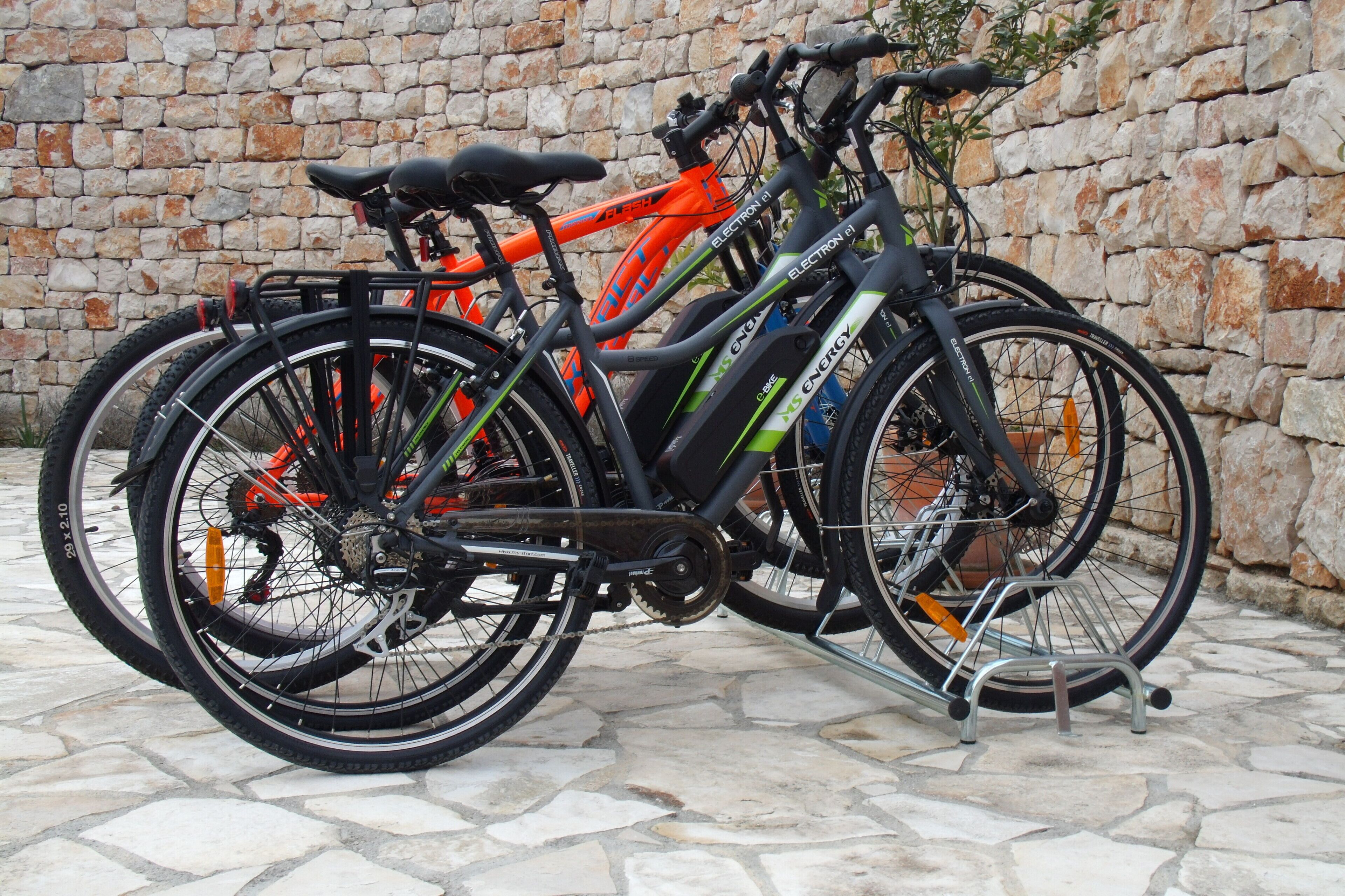 Una bicicletta appoggiata a un muro di pietra.
