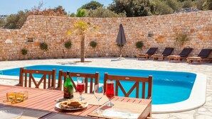 Un espace repas aménagé au bord de la piscine, avec une table dressée pour deux personnes, une bouteille de vin et des verres.